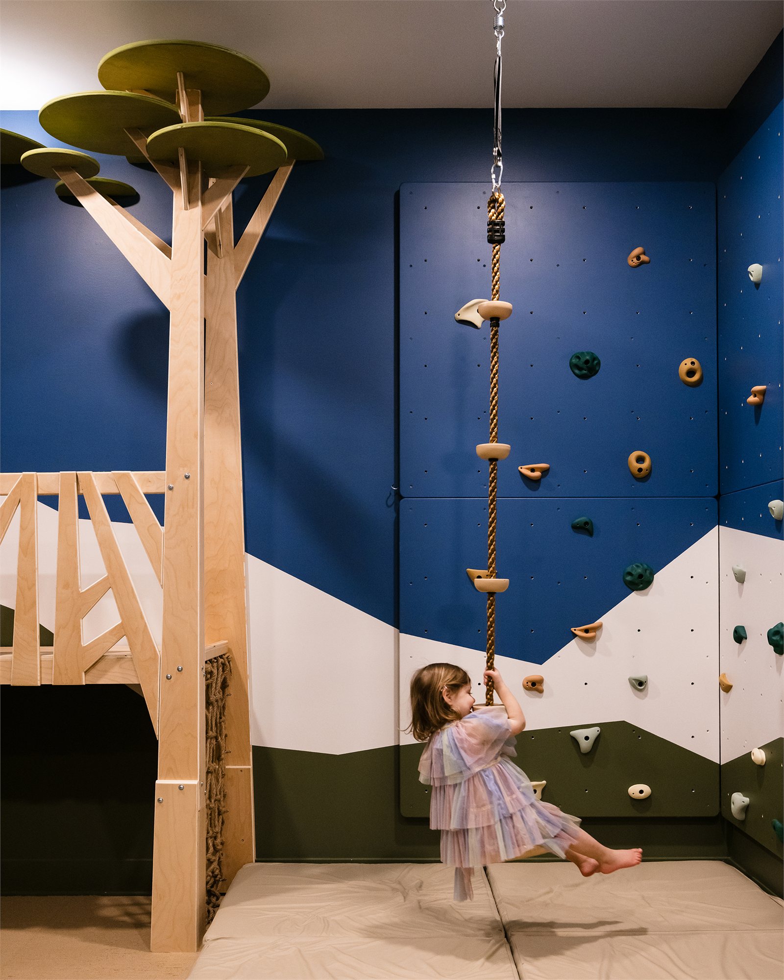 A nature themed children's playroom with custom built-in tree structures and climbing features